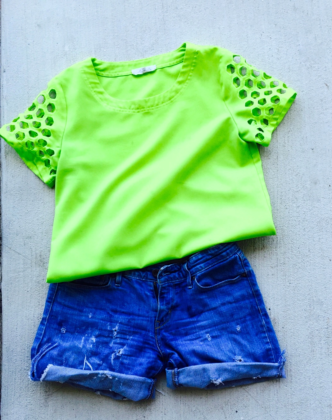 neon green top with cut out holes, denim shorts
