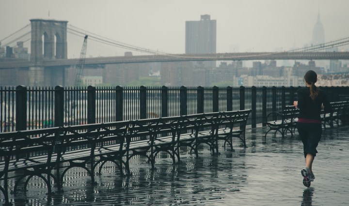 girl running outside by a bridge