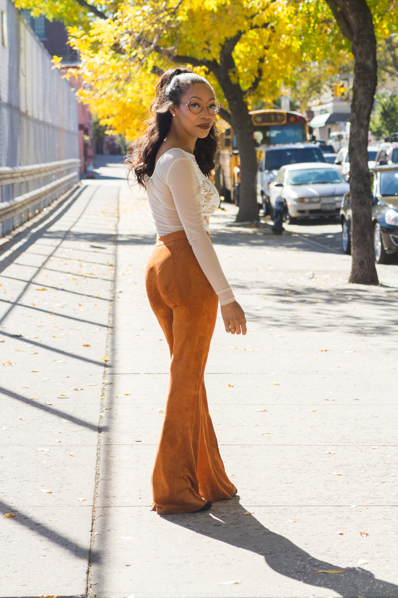 Sade Spence wearing rust colored suede flares and white sheer bodysuit blue labels boutique