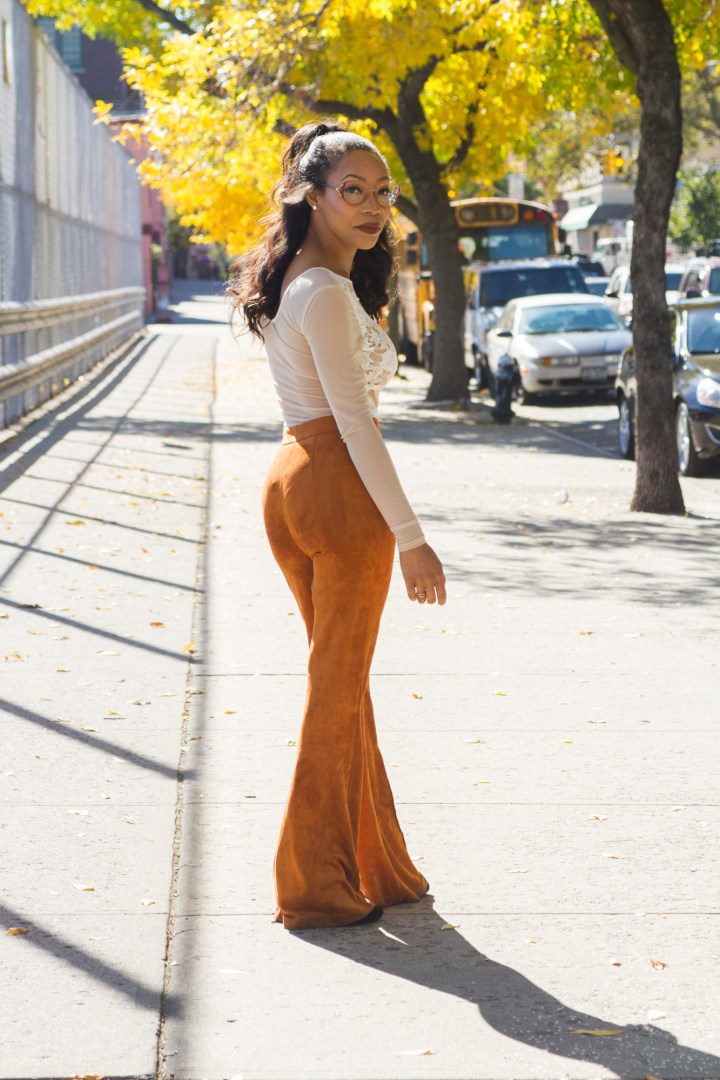 Sade Spence wearing rust colored suede flares and white sheer bodysuit blue labels boutique